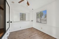 Bright and airy room with elegant wood flooring, large mirrored closet, and abundant natural light through sizable windows.