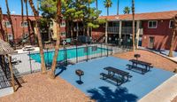 Inviting apartment complex showcasing a sparkling swimming pool, surrounded by cozy seating areas and lush palm trees.