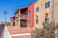 Charming apartment building with colorful stucco facade, balconies, and vibrant landscaping under a clear blue sky.