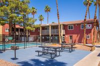 Charming apartment complex with a beautiful pool area and outdoor seating, surrounded by lush palm trees and vibrant landscaping.