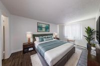 Elegant bedroom with a plush king-sized bed, modern decor, and abundant natural light from vertical blinds.