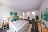Inviting bedroom with elegant decor, featuring a plush bed, modern nightstands, and vibrant art, surrounded by stylish flooring and soft lighting.