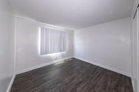 Bright and airy room with modern dark wood flooring and vertical blinds, perfect for creating a cozy and inviting living space.