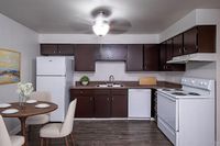 Modern kitchen with sleek dark cabinets, a cozy dining area, and contemporary appliances creating a welcoming atmosphere.