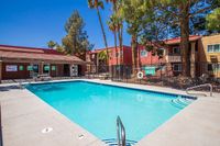 Vibrant apartment complex with a pristine swimming pool surrounded by lush palm trees and welcoming outdoor seating.