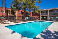 Vibrant apartment complex featuring a sparkling swimming pool surrounded by lush palm trees, perfect for relaxation and leisure.