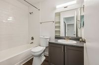 Modern bathroom featuring sleek white tiling, elegant vanity, and a spacious bathtub for ultimate relaxation.