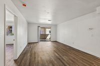Bright and spacious living room with warm wood flooring, leading to a cozy outdoor patio through sliding glass doors.