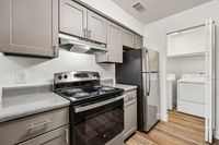 Modern kitchen with sleek stainless steel appliances, elegant cabinetry, and in-unit laundry for convenient living.