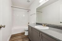 Modern bathroom with sleek design featuring a spacious vanity, polished granite countertop, and elegant fixtures, complemented by a pristine bathtub and contemporary flooring.