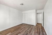 Spacious bedroom with sleek wooden floors, bright white walls, and ample closet space.