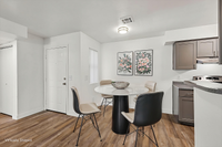 Chic dining area with a round table and elegant seating, accentuated by floral wall art and sleek kitchen cabinetry.