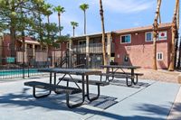 Charming apartment complex with palm trees, a refreshing pool, and outdoor seating, perfect for relaxation in a sunny setting.