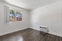Bright and inviting room with elegant wood flooring, a large window offering a scenic view, and a convenient wall-mounted air conditioner.