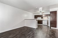 Charming open-concept living area with dark wood floors, featuring a modern kitchen with rich cabinetry and a cozy breakfast bar.