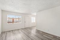 Bright and airy living space with modern hardwood flooring, enhanced by natural light through large windows.