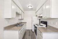 Bright, galley-style kitchen with modern white cabinets, sleek countertops, and a functional layout.