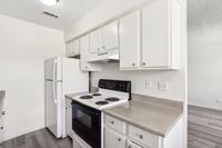 Modern kitchen with sleek white cabinetry, electric stove, and spacious countertops in a bright, inviting space.