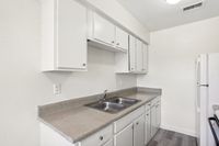 Modern kitchen with sleek white cabinets, spacious countertops, and a double sink.