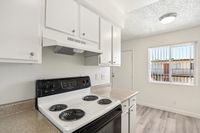 Bright kitchen with modern white cabinetry, electric stove, and a large window for natural light.