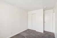 Bright and spacious bedroom with plush carpeting and sleek white closet doors, perfect for modern living.