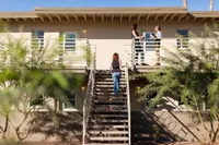 rear of 2 story apartment building with woman climbing the staircase  at oasis 20