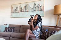 woman holding dog while sitting on sofa at oasis 20
