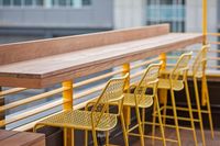 bar with yellow bar chairs at oro apartments rooftop