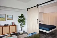 Slabtown, OR Apartments - ORO - Furnished Living Room And Bedroom With Wood-Style Flooring, A Barn Door, And A Large Closet