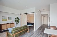One BR Apartments in Downtown Portland OR - ORO - An interior shot of The Open-Concept Living Room Area with Large Sofa, Potted Plant, and Area Rug
