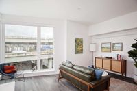 Pearl District OR Apartments - ORO - Living Room With High Ceilings, Wood-Style Flooring, And Floor-to-Ceiling Windows Overlooking the City.