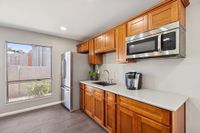 Community kitchen with refridgerator, microwave, window view and wooden counters and cupboards