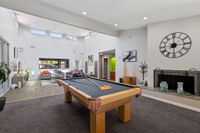 Games room with pool table, seating, plants, and windows in an open space