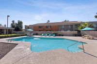 Pool with lounge chairs, sun, bushes, and table and chair sets