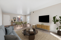 virtually staged living room at Bridge Lane with a couch, coffee table, tv, console and plant and showing view into dining room