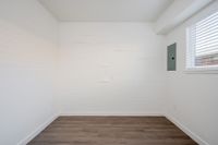 Bedroom with wooden floor and window and circuit breaker.