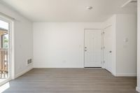 Living area with wooden floor, doors, patio, and vents.