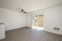Living area with wooden floors, fan, patio, and vent.