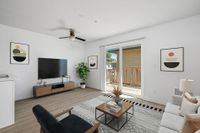 virtually staged living room with sofa, chair, table, tv, patio, ceiling fan, and artwork.