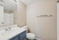 Bathroom vanity with a blue cabinet, white speckled countertop, and large wall mirror.
