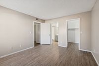 Bedroom view showing vinyl plank floors and open doors to the closet and bathroom areas.