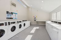 Bright laundry facility with rows of white front-loading washing machines.