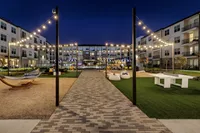 Elegant apartment courtyard with twinkling string lights, outdoor seating, and recreational amenities at night.