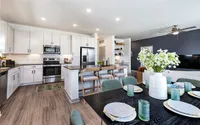 Modern kitchen with sleek appliances, bar seating, and stylish dining table set for guests with elegant decor.