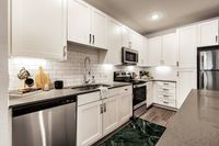 Modern kitchen interior with sleek white cabinets, stainless steel appliances, and a stylish backsplash.