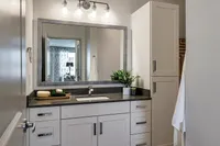 Modern bathroom with sleek vanity, large mirror, and elegant lighting.