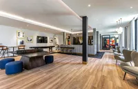 Spacious modern lounge with stylish seating, sleek wooden flooring, and minimalistic decor.