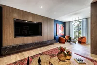 Chic modern living room with wood paneling, large TV, vibrant artwork, and elegant lighting.