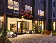 Elegant exterior view of The Palmer apartment complex, showcasing stylish brickwork and welcoming entrance.