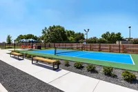 Beautifully maintained outdoor tennis court with benches and a scenic backdrop.